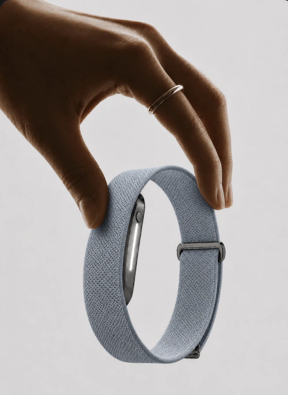A hand lifting a Haven band by its woven strap